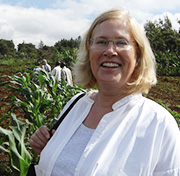 A happy person outdoors in a field with agricultural workers in the background
